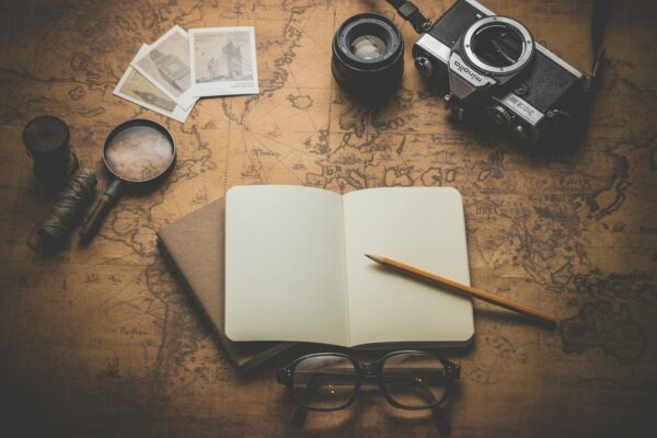 flat ray photography of book, pencil, camera, and with lens