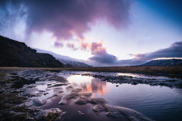 A body of water surrounded by mountains and clouds