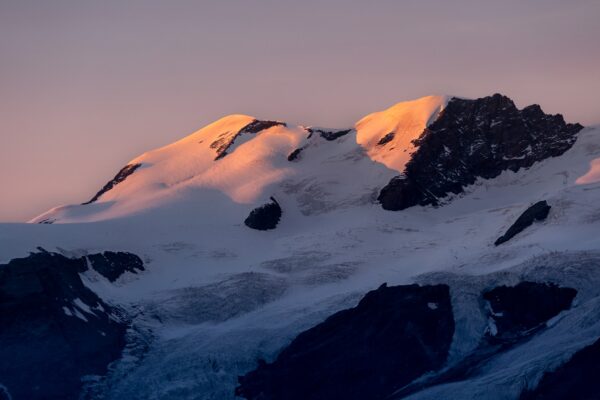 A mountain covered in snow at sunset