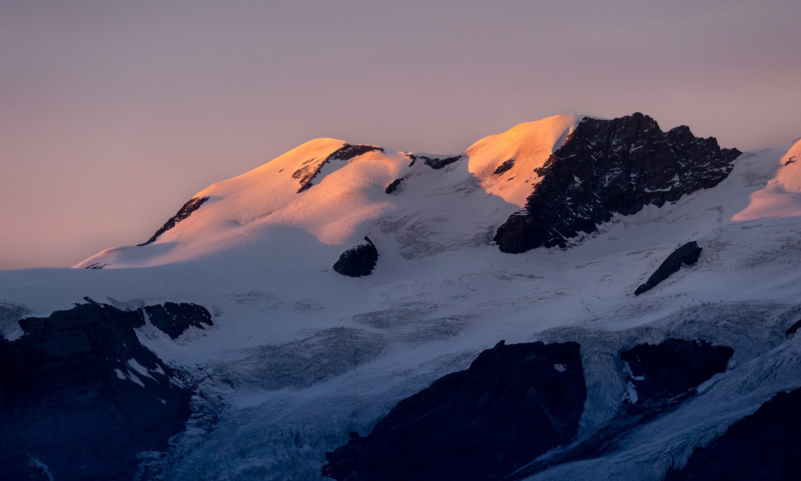 A mountain covered in snow at sunset