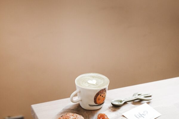 white ceramic teacup on saucer beside bread on table