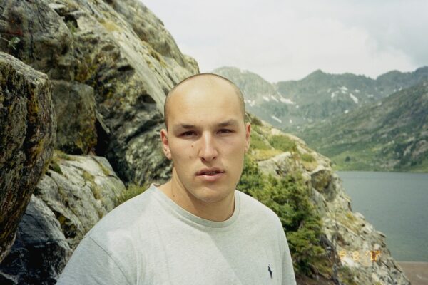 man in white crew neck shirt standing on rocky mountain during daytime