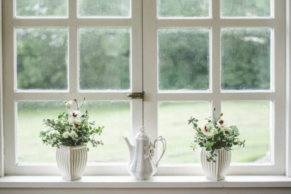 white teapot and tow flower vases on windowpane