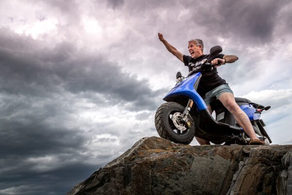 man in black jacket and blue denim jeans riding blue and white motorcycle